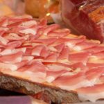 Immagine di un piatto con prosciutto crudo, evidenziando i rischi per la salute.