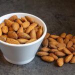 Un piatto di mandorle tostate, pronte per essere gustate, illustrate in un articolo sulla quantità giornaliera consigliata.