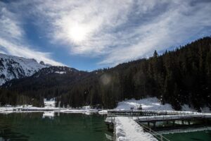 Lago di Braies circondato da montagne delle Dolomiti, riflesso blu nell'acqua cristallina.
