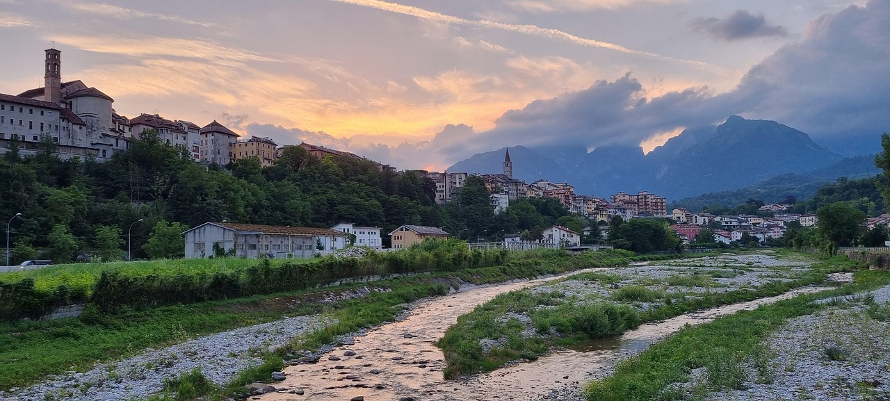 Valle trentina con paesaggi mozzafiato, verdi colline e cieli azzurri, simile a un dipinto naturale.