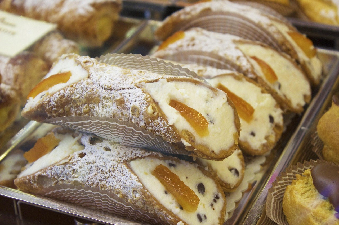 Deliziosi cannoli siciliani con crema di ricotta e gocce di cioccolato su sfondo rustico.