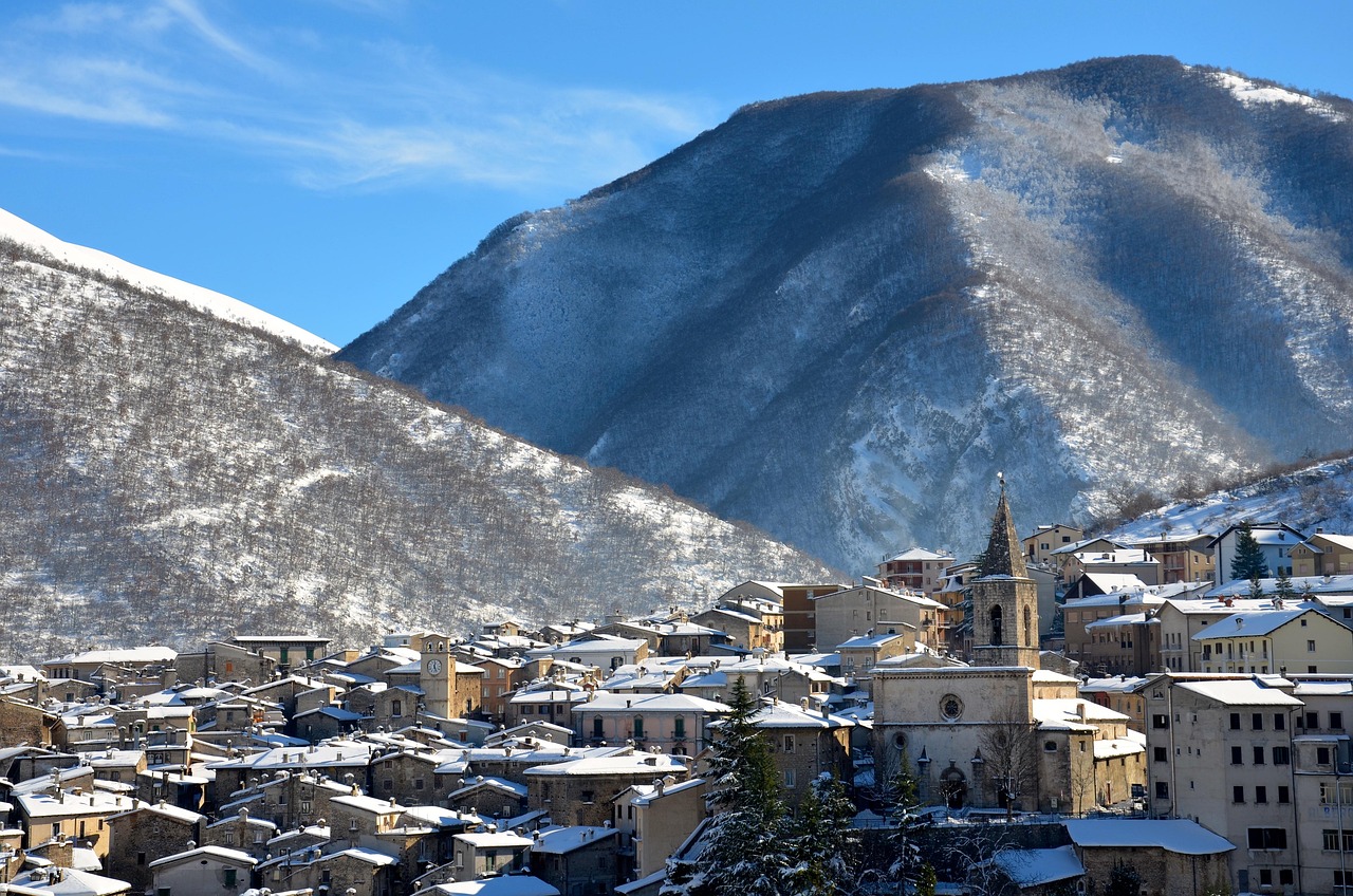 Borgo italiano innevato con case in pietra e luci soffuse durante l'inverno.