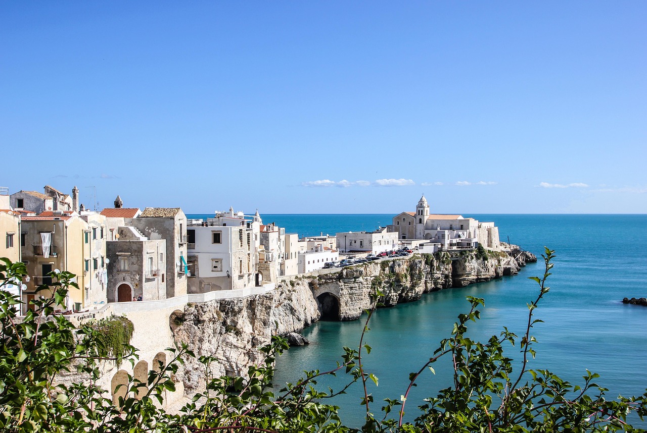 Borgo medievale in Puglia con case bianche e mare cristallino, ideale per una visita estiva.